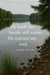 A calm lakeside with still water reflecting trees and sky, paired with the verse “He leads me beside still waters. He restores my soul.” from Psalm 23:2–3a